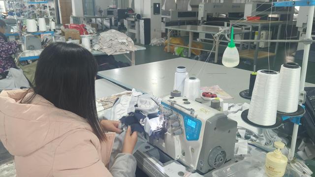 Production facility showing workers processing apparel items on assembly tables.