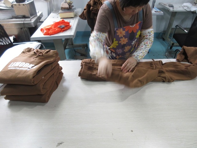 Proceso de planchado y verificación dimensional final de camisas industriales