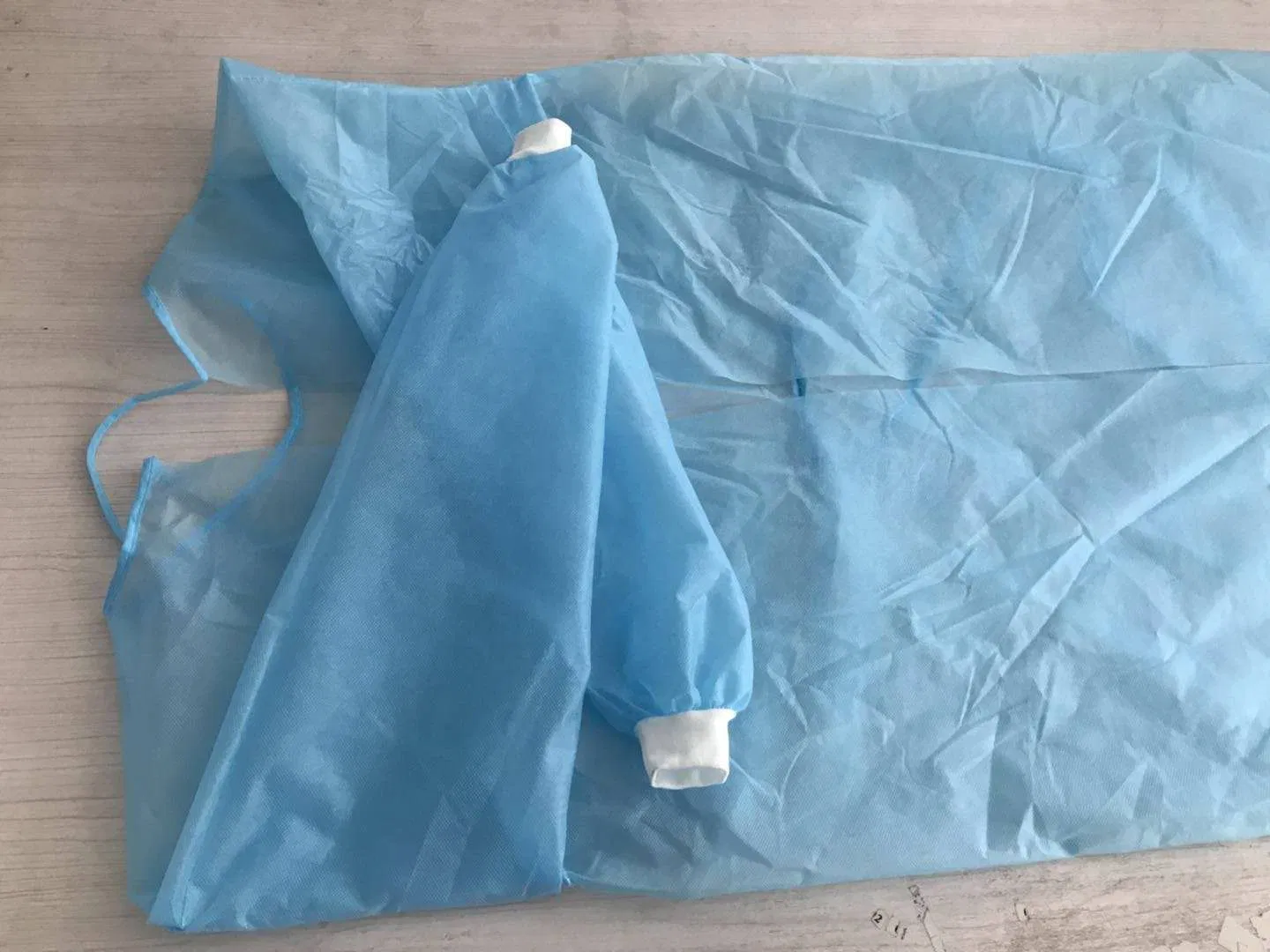Fabricante chino de bata de aislamiento no tejida barata con puños de punto