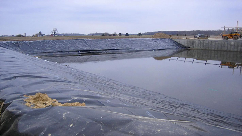 Construction worker laying geomembrane