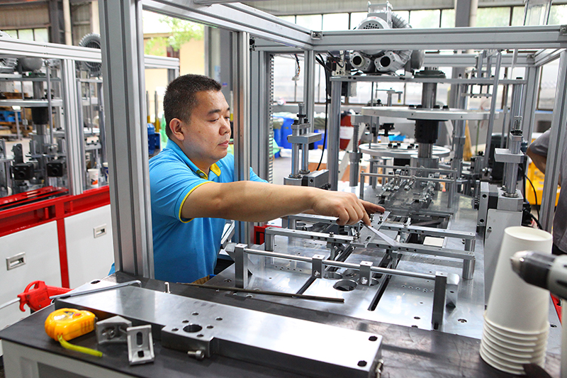 Huanqiang Machinery engineering team working on paper cup machine development