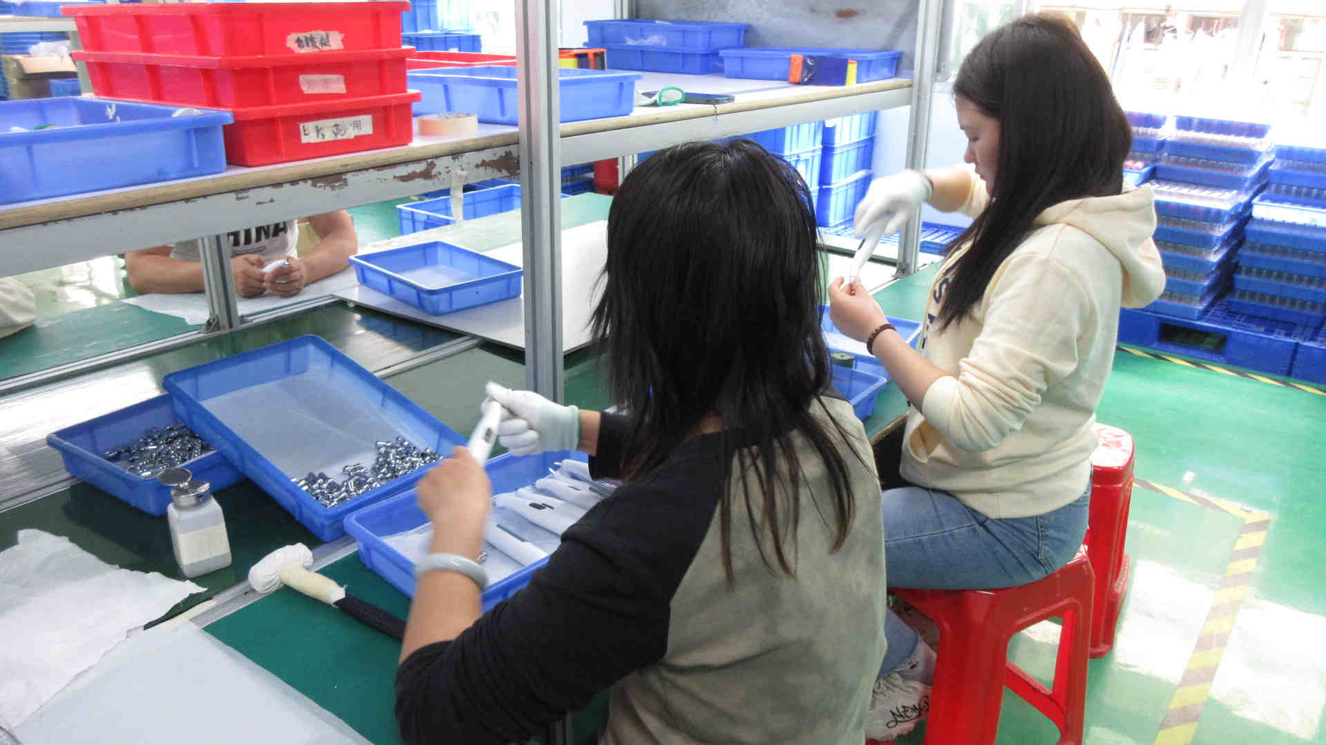 Assembly worker completing beauty device units at Kelli Beauty production line