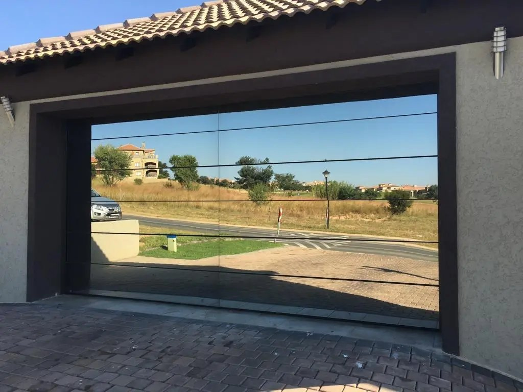 أبواب جراج مصممة حديثًا بالكامل من الألمنيوم والزجاج مع زجاج أسود لمنزل فيلا