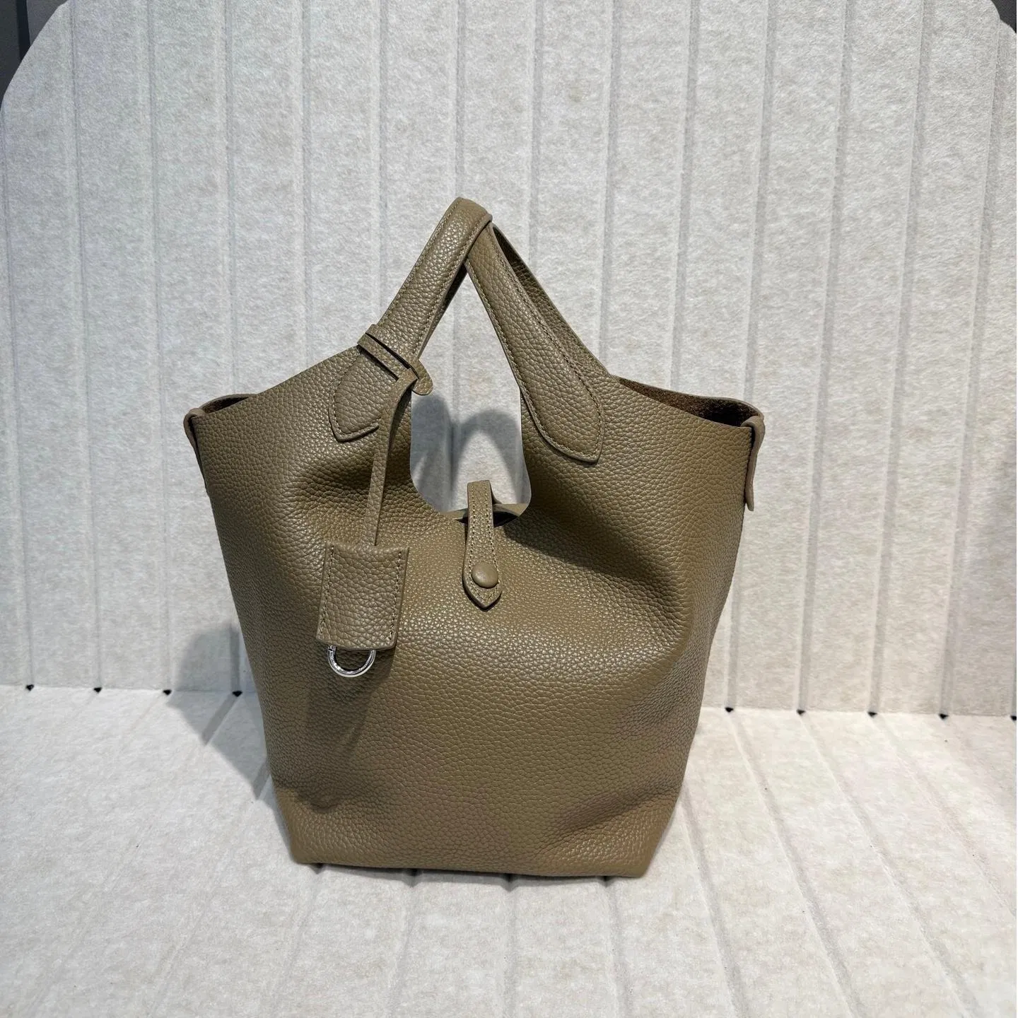 2025 Nueva bolsa de cesta de verduras de piel de vaca con grano de lichi, versión coreana del estilo minimalista, bolso casual tipo cubo para mujeres