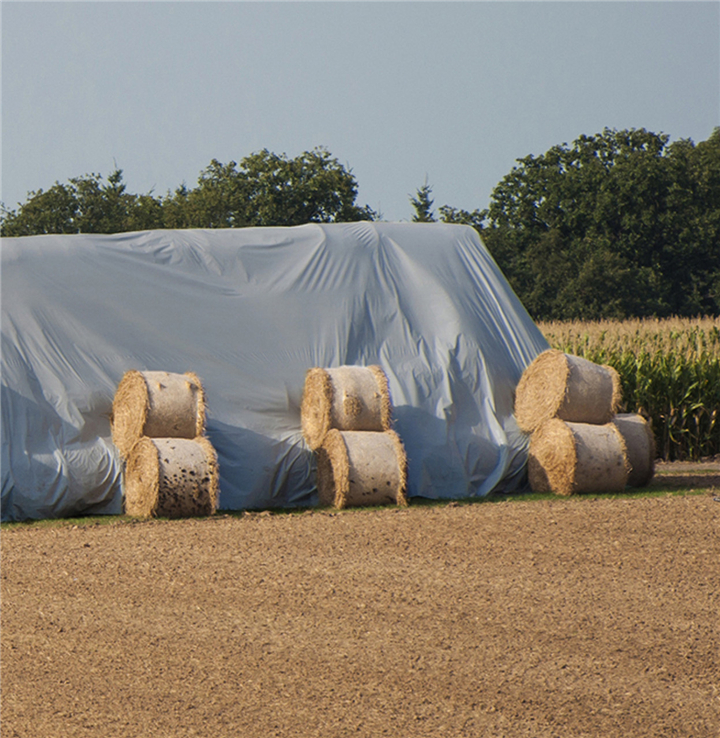 Agriculture tarpaulin covering hay and grain on farmland